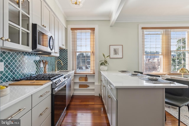 kitchen with ornamental molding, a kitchen breakfast bar, stainless steel appliances, a peninsula, and decorative backsplash