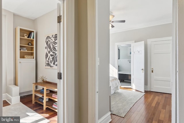 corridor with wood finished floors, baseboards, and ornamental molding