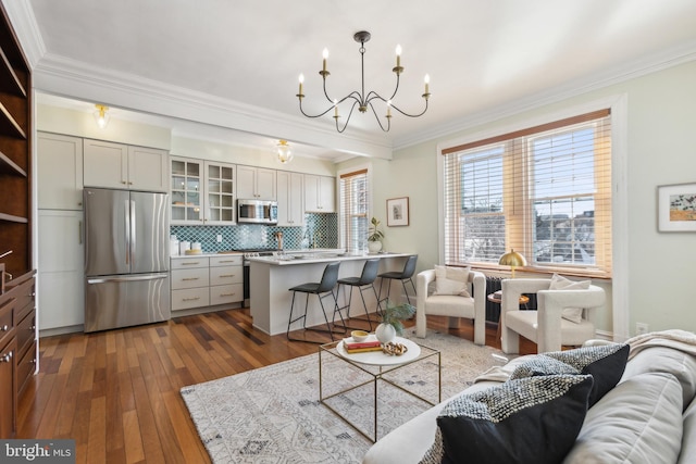 living room featuring dark wood-style floors, an inviting chandelier, and ornamental molding