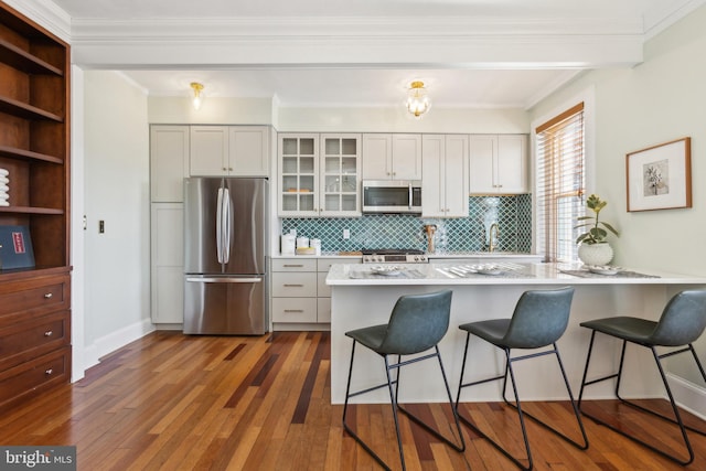 kitchen with hardwood / wood-style floors, a kitchen breakfast bar, appliances with stainless steel finishes, and a peninsula