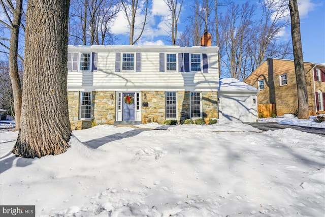 colonial house featuring stone siding, a chimney, and a garage