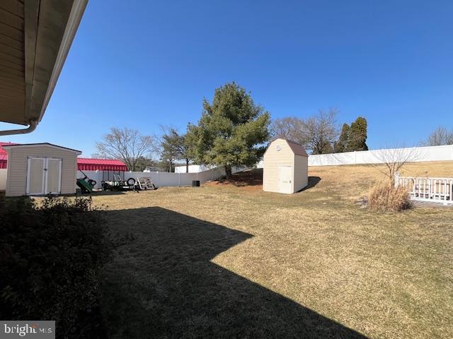 view of yard featuring an outdoor structure, a fenced backyard, and a shed