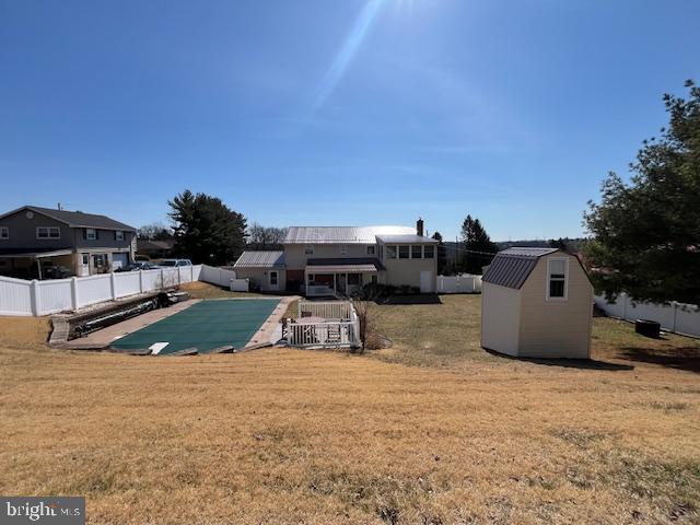 exterior space with a fenced in pool, a shed, a yard, a fenced backyard, and an outbuilding