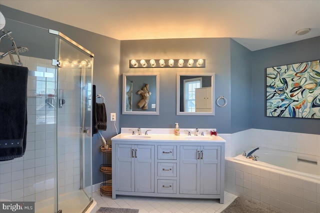 bathroom featuring tile patterned flooring, a stall shower, a bath, and a sink