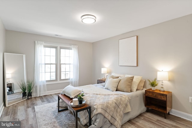 bedroom featuring baseboards, visible vents, and light wood finished floors