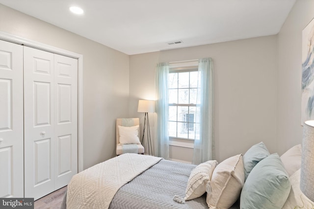 bedroom with recessed lighting, visible vents, a closet, and wood finished floors