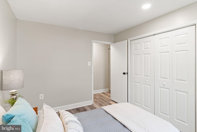 bedroom featuring wood finished floors, baseboards, and a closet