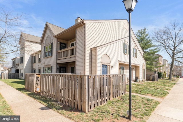 view of side of property with fence, a residential view, and a chimney