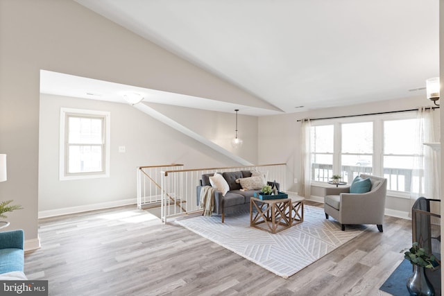 living area featuring baseboards, lofted ceiling, and wood finished floors