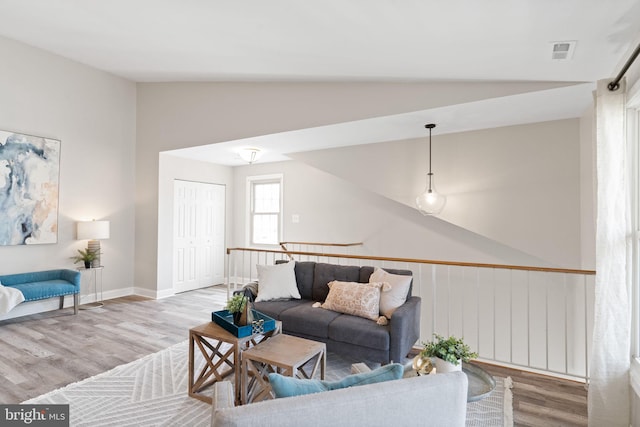 living area featuring visible vents, wood finished floors, baseboards, and vaulted ceiling