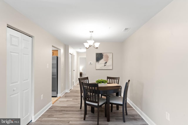 dining room with visible vents, baseboards, an inviting chandelier, and light wood-style flooring