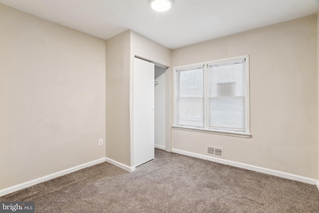 unfurnished bedroom featuring a closet, visible vents, baseboards, and carpet floors