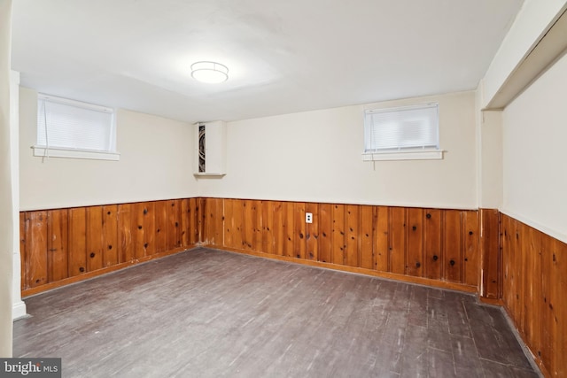 basement with a wainscoted wall, wooden walls, and wood finished floors