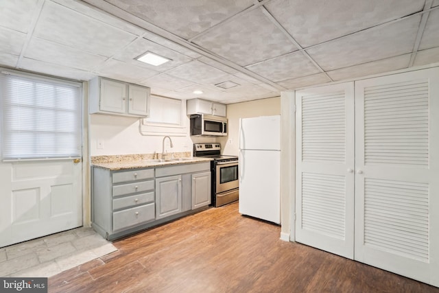 kitchen featuring a sink, light wood-type flooring, appliances with stainless steel finishes, and gray cabinetry