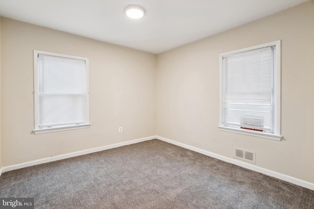 spare room featuring baseboards, visible vents, and carpet floors