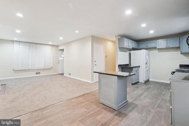 kitchen with dark countertops, recessed lighting, range, and white fridge with ice dispenser