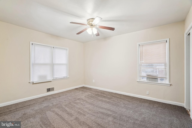 carpeted spare room with baseboards, visible vents, and ceiling fan