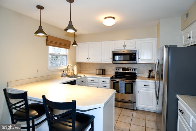 kitchen with a peninsula, a kitchen breakfast bar, white cabinets, stainless steel appliances, and a sink