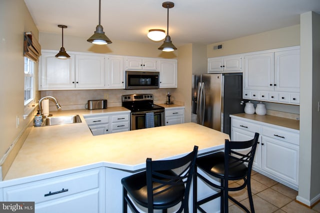 kitchen featuring a peninsula, a sink, appliances with stainless steel finishes, white cabinetry, and tasteful backsplash