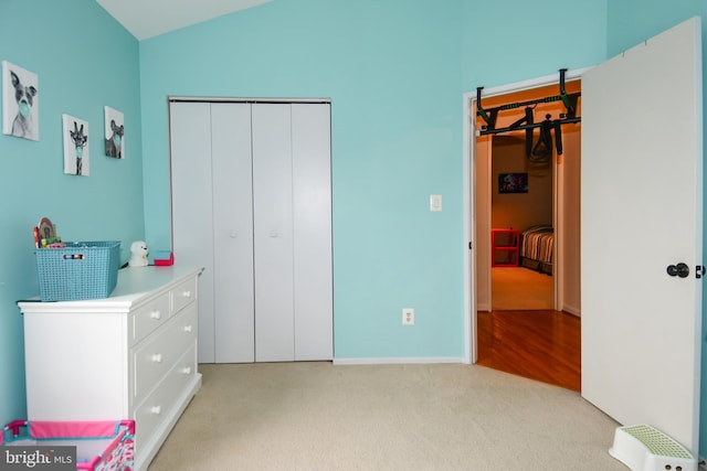 bedroom with vaulted ceiling, light colored carpet, and a closet