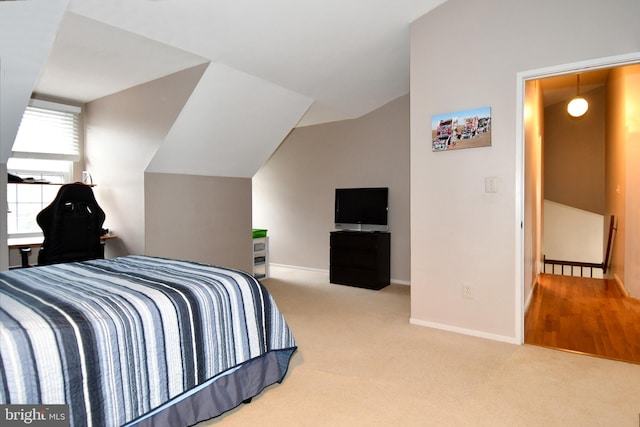 carpeted bedroom featuring lofted ceiling and baseboards