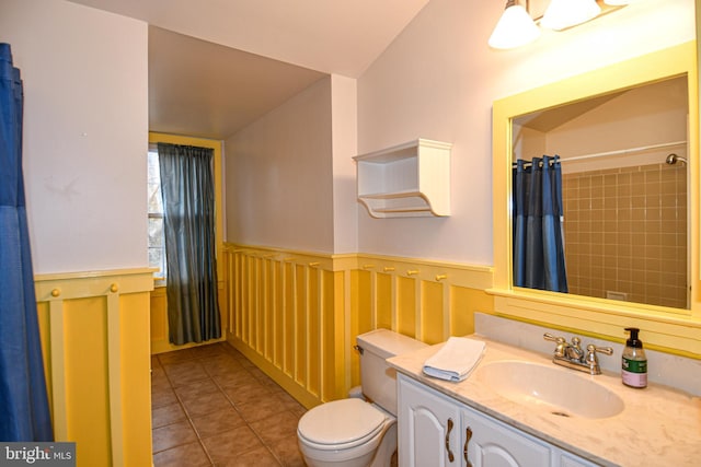 bathroom with vanity, a shower with shower curtain, wainscoting, tile patterned floors, and toilet