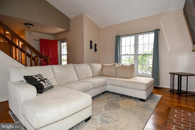 living area featuring baseboards, lofted ceiling, wood finished floors, and stairs