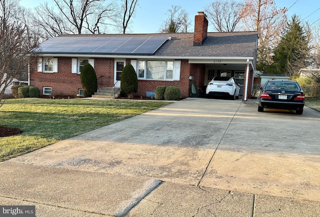 ranch-style home featuring brick siding, an attached carport, concrete driveway, a front yard, and roof mounted solar panels