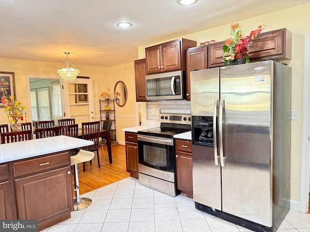 kitchen with tasteful backsplash, appliances with stainless steel finishes, light countertops, and a kitchen bar