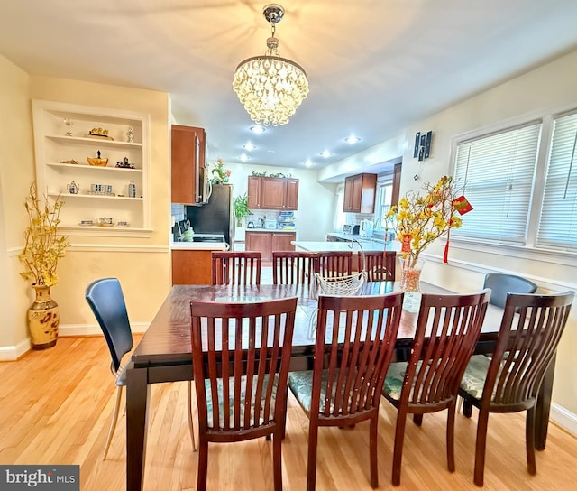 dining room featuring baseboards, light wood-type flooring, and a chandelier