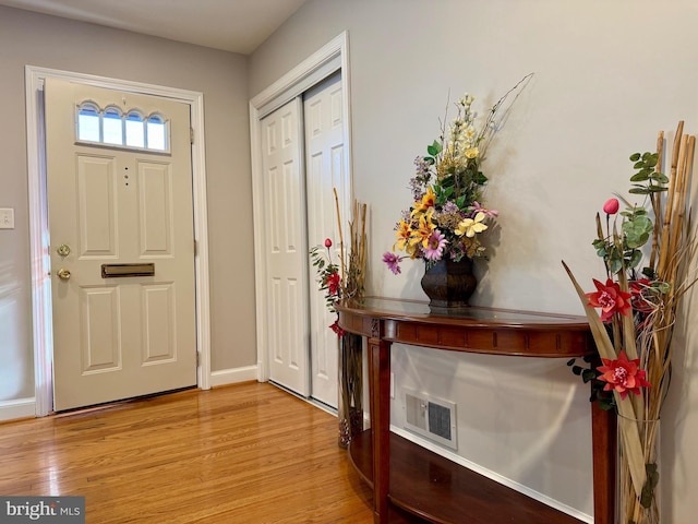 foyer entrance with visible vents, baseboards, and light wood finished floors