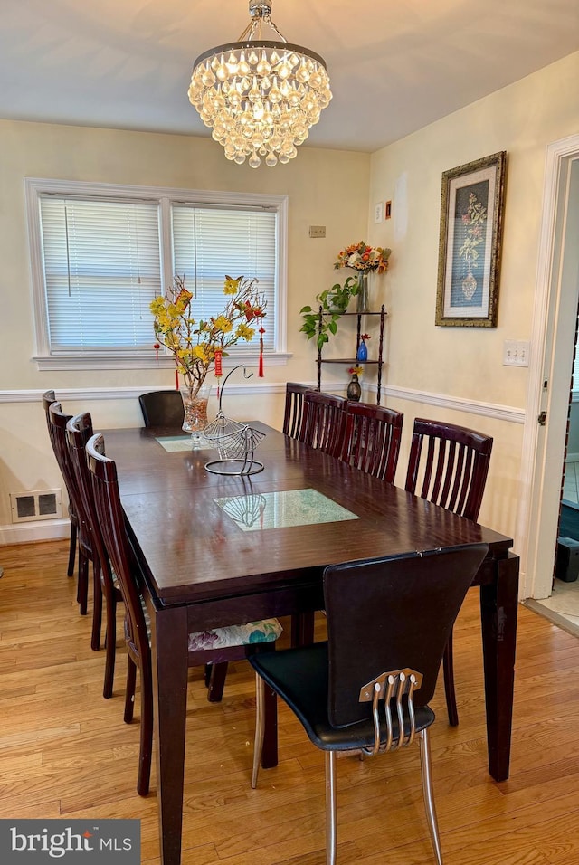 dining area with a notable chandelier, visible vents, and light wood-style flooring