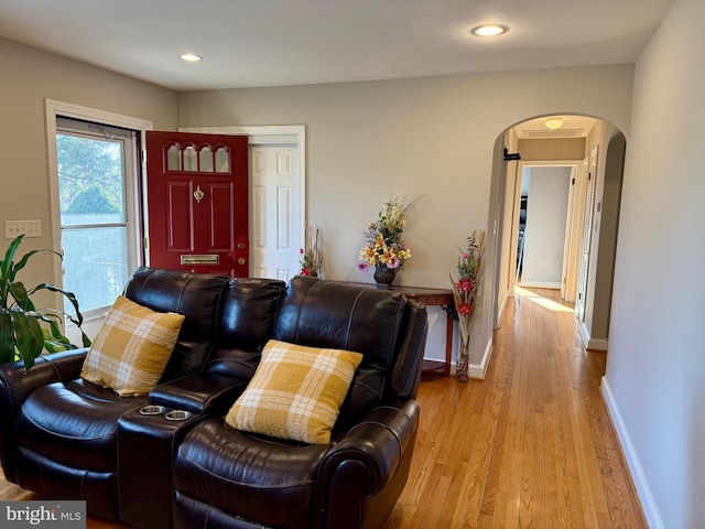 living area with recessed lighting, wood finished floors, arched walkways, and baseboards