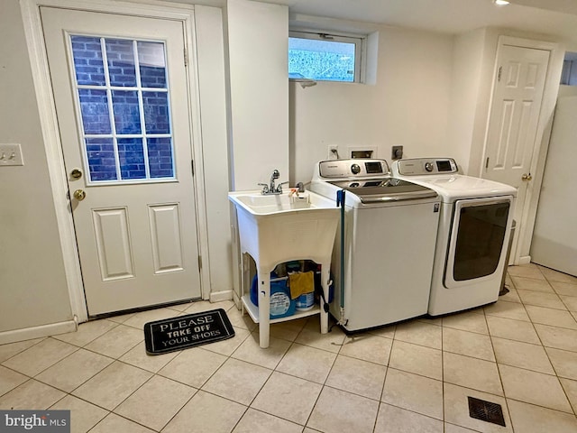 laundry room featuring baseboards, light tile patterned flooring, laundry area, and washing machine and clothes dryer