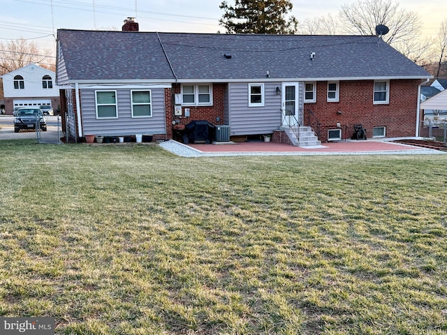 rear view of property with a lawn, a shingled roof, a chimney, and fence