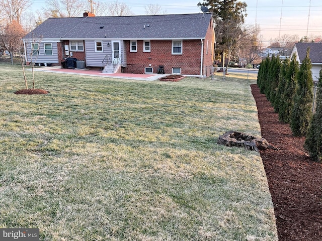 rear view of property with a lawn, entry steps, fence, brick siding, and a patio area