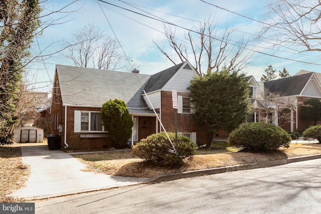 view of front of property featuring brick siding, a chimney, and an outdoor structure