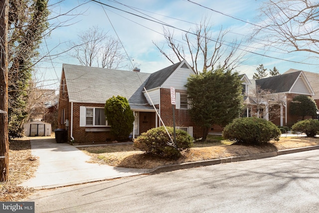 view of front of property featuring brick siding, a chimney, and an outbuilding