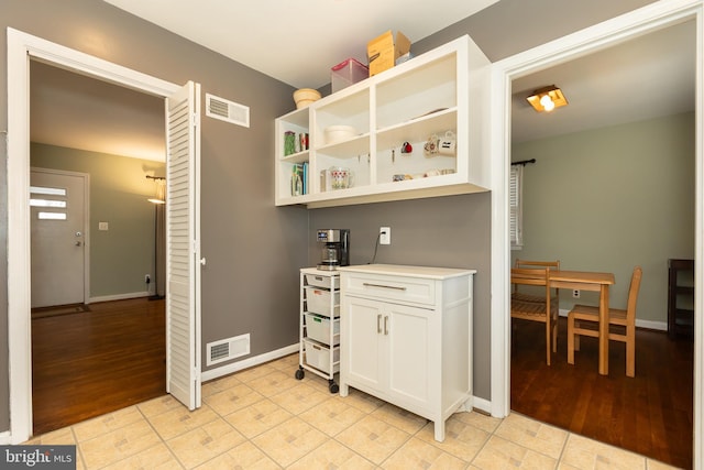 interior space with visible vents, baseboards, and white cabinetry