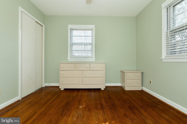 unfurnished bedroom featuring dark wood finished floors, a closet, and baseboards