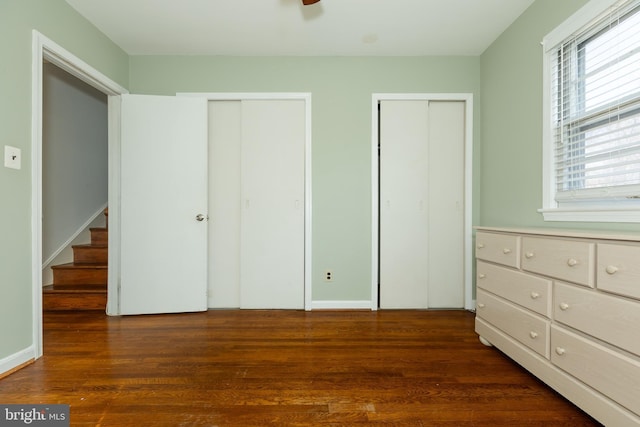 unfurnished bedroom featuring wood finished floors and two closets