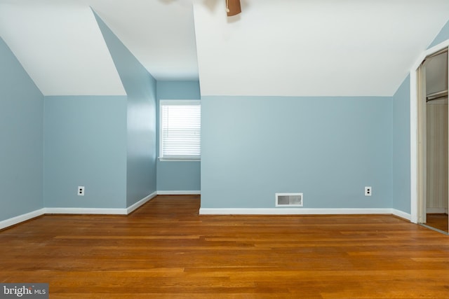 bonus room featuring vaulted ceiling, visible vents, baseboards, and wood finished floors