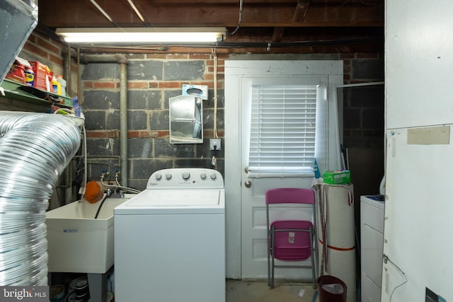 washroom featuring laundry area, washer / clothes dryer, brick wall, and a sink