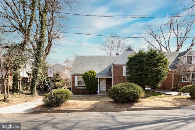 view of front of home featuring brick siding and a chimney