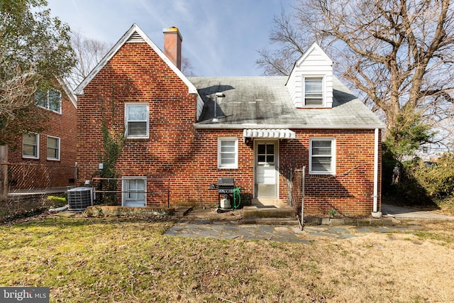 rear view of house with fence, brick siding, central AC, and a lawn