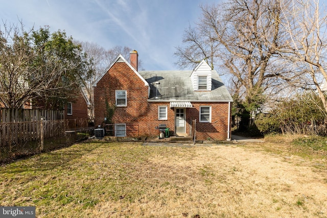 view of front of home with brick siding, fence, central AC, a front yard, and a chimney