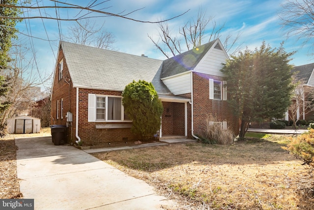 view of front of house with an outdoor structure, concrete driveway, and brick siding