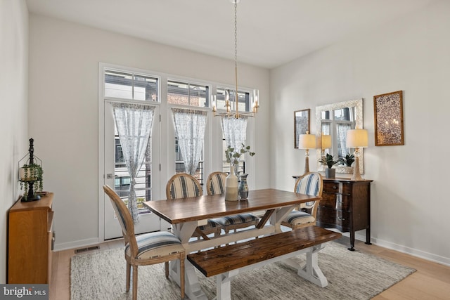 dining space with a notable chandelier, a healthy amount of sunlight, visible vents, and light wood-type flooring