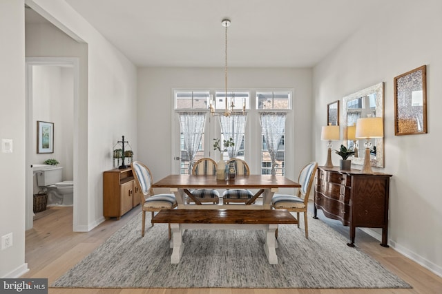 dining area featuring baseboards, an inviting chandelier, and light wood-style flooring