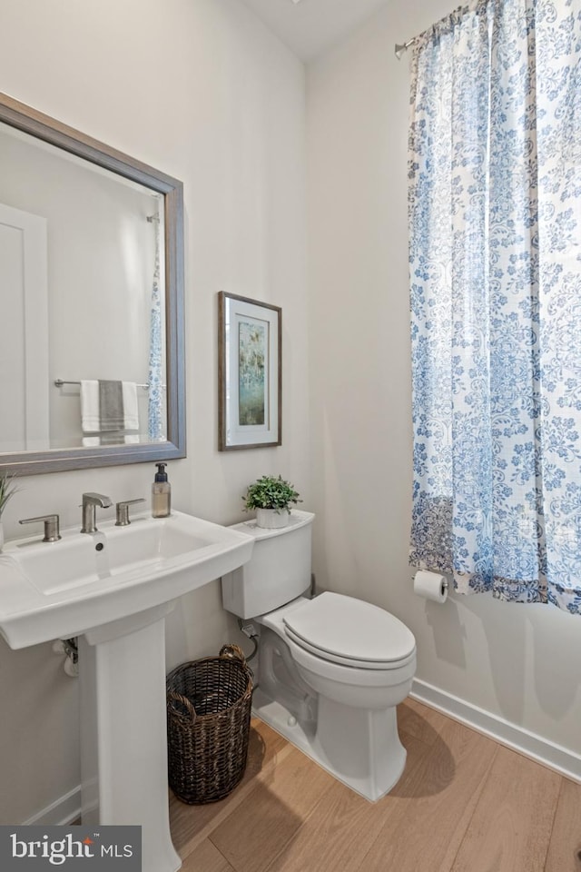 bathroom featuring a sink, baseboards, toilet, and wood finished floors